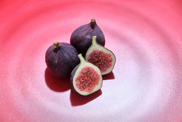 Fresh ripe figs cut in half on a red background with the effect of water waves. Fresh summer fruits.