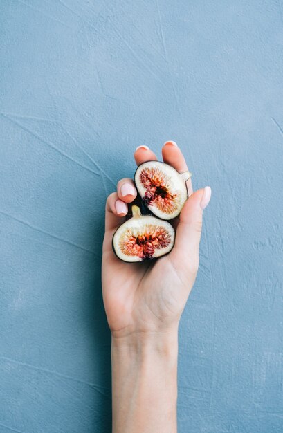 Photo fresh ripe figs in hand on blue background, close-up.