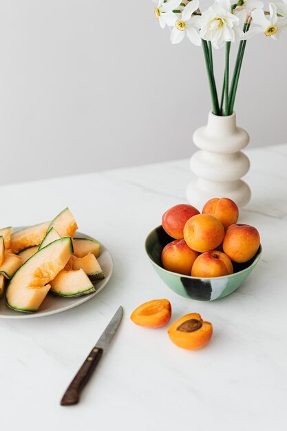 Fresh ripe fruits served on table with vase of delicate flowers