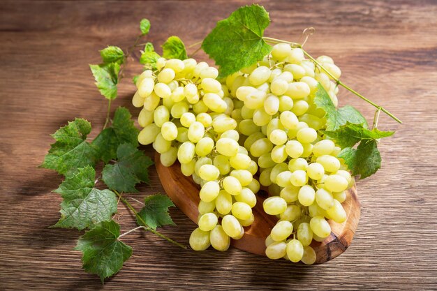 Photo fresh ripe grape with leaves on a wooden board