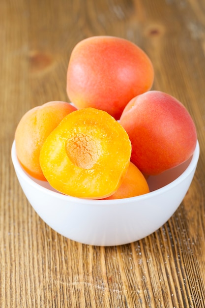 Fresh ripe and juicy beautiful apricots in a bowl on a table, closeup