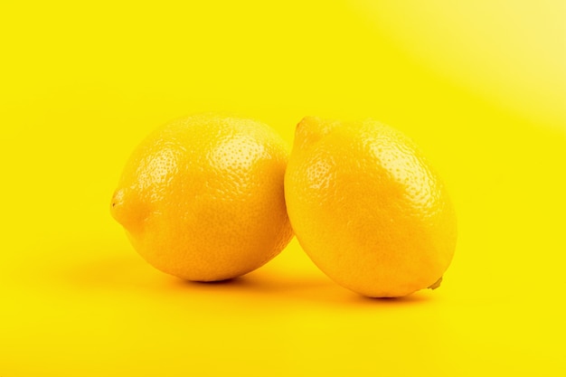 Fresh ripe lemons isolated on yellow background.