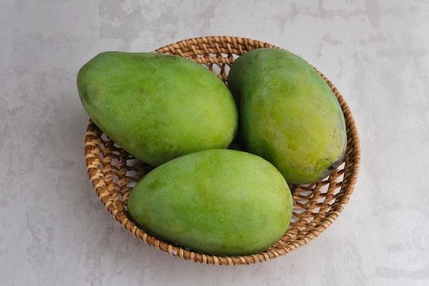 Photo fresh and ripe mango fruit served in rattan basket on grey background close up