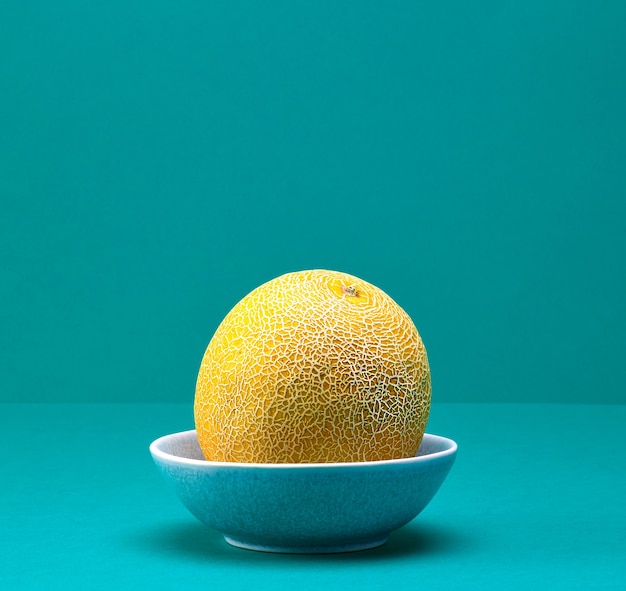 Fresh ripe melon in a bowl on turquoise color background