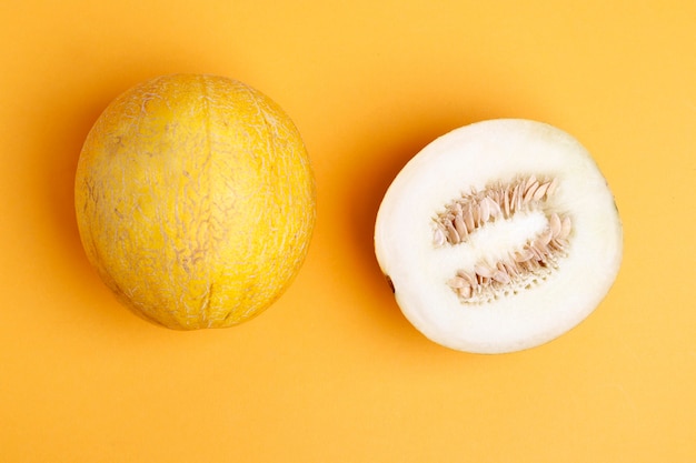 Fresh ripe melon on orange background. a piece of melon cut in half. flat laãâãâ