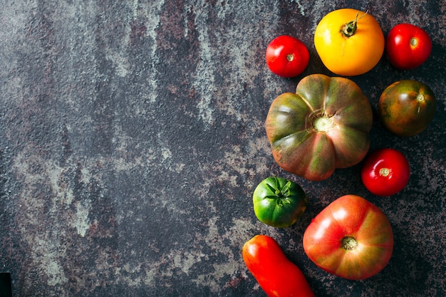 Fresh, ripe multi colored tomatoes on a dark background.