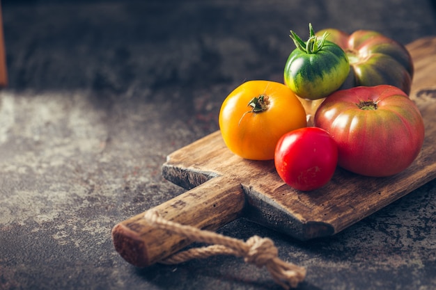 Fresh, ripe multi colored tomatoes on a dark background.