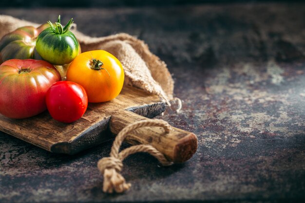 Fresh, ripe multi colored tomatoes on a dark background.