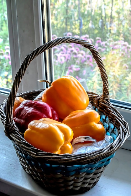 Photo fresh ripe multicolored peppers in a basket on the windowsill