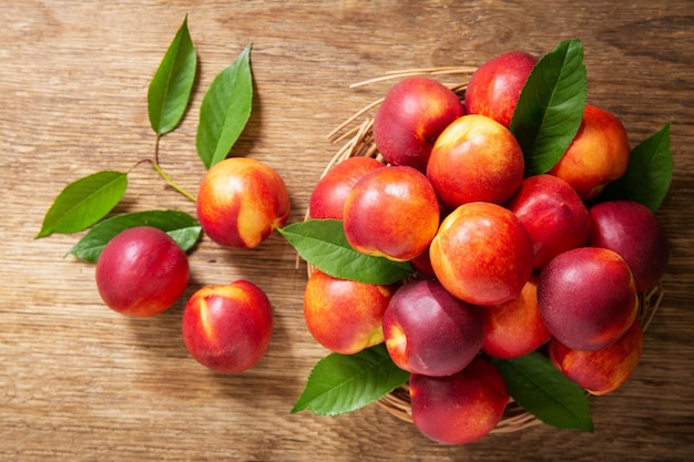 Fresh ripe nectarines with leaves on a wooden table