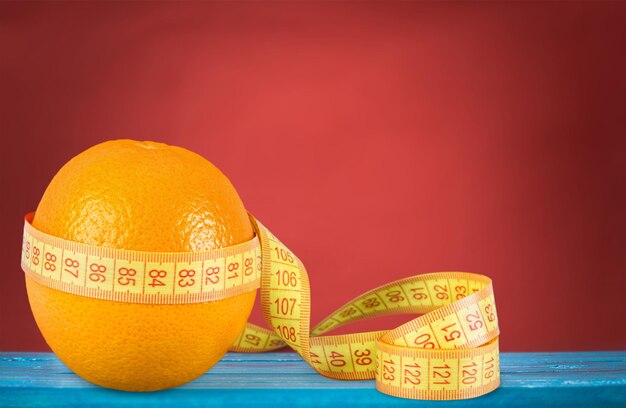 Fresh ripe orange wrapped with measuring tape