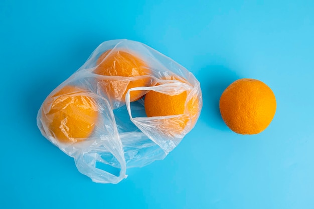 Fresh ripe oranges in a transparent plastic bag on a blue background Top view flat lay
