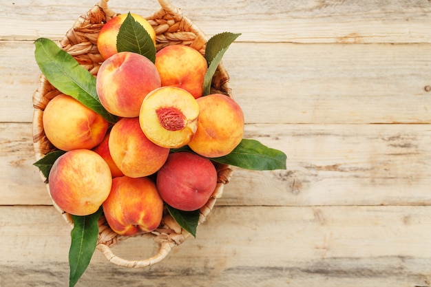 Fresh ripe peaches in a wicker basket on a wooden table