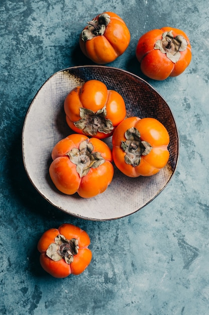 Fresh ripe persimmon on blue background.