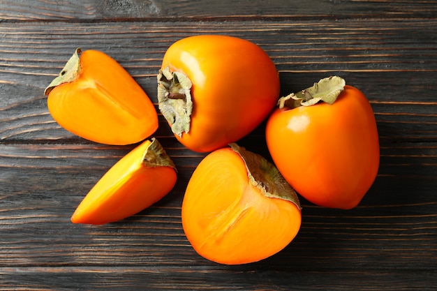 Fresh ripe persimmon on wooden background, top view