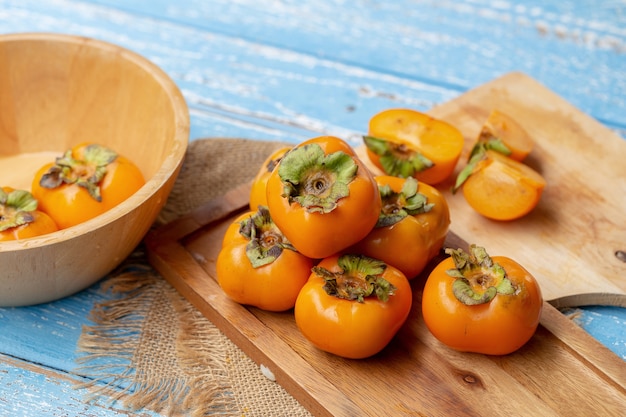 Fresh ripe persimmons on blue wooden table