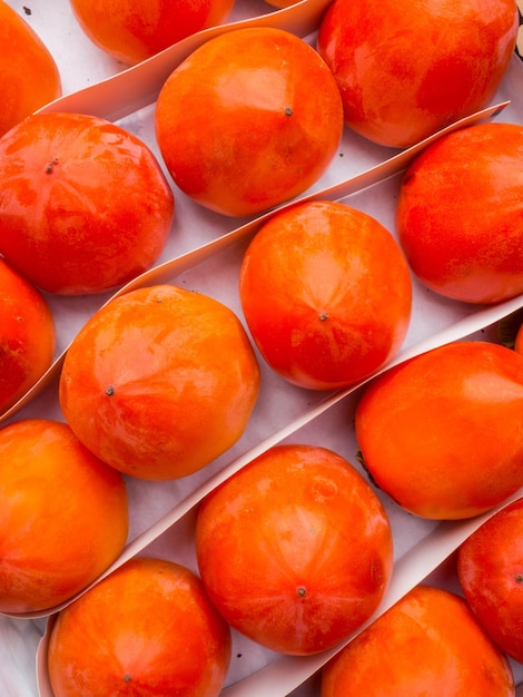 Fresh ripe persimmons in market Organic persimmon fruit in pile at local farmers market Persimmons background