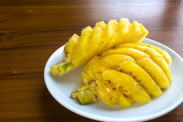 Fresh ripe pineapple in a disk on wooden table