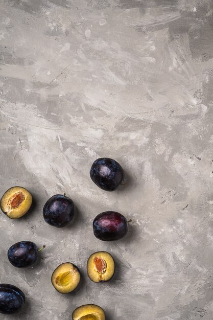 Fresh ripe plum fruits whole and sliced on stone concrete