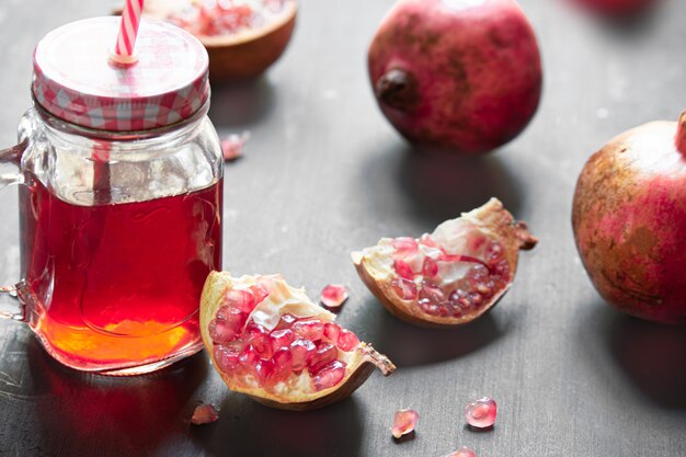 Fresh ripe pomegranate and glasses of pomegranate juice on old wooden table