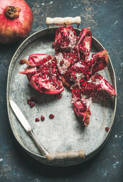 Fresh ripe pomegranate in metal tray over dark blue background