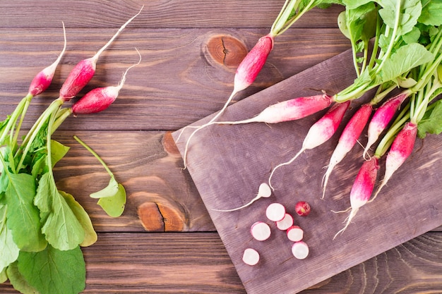 Fresh ripe radish cut into pieces on a cutting board on a wooden table. Top view