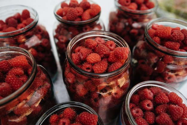 Fresh, ripe raspberries in small jars close-up