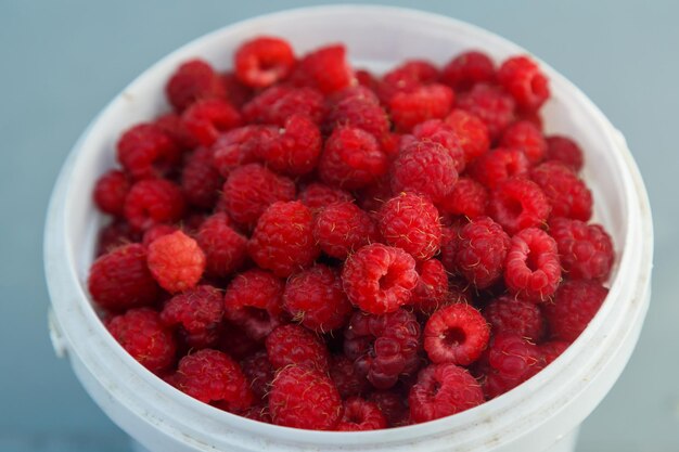 Fresh ripe raspberries in a white bowl on the table