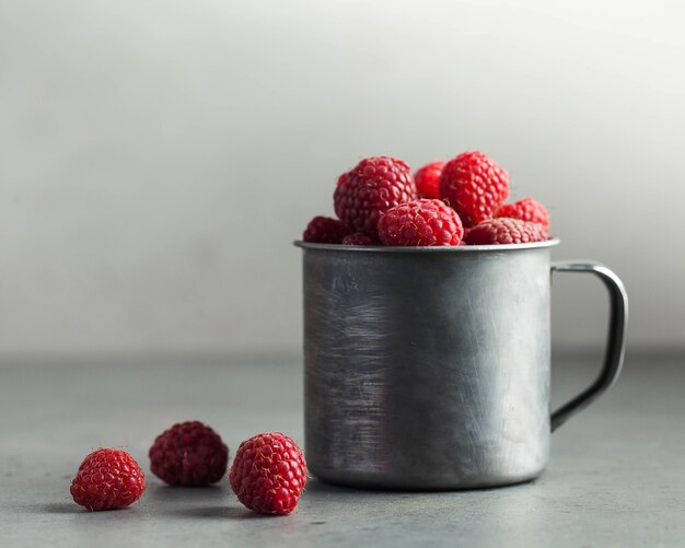 Fresh ripe raspberries in a wooden bowl on gray