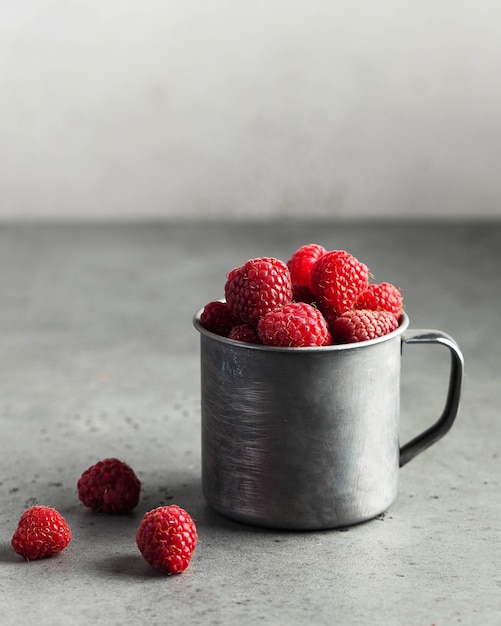 Fresh ripe raspberries in a wooden bowl on gray