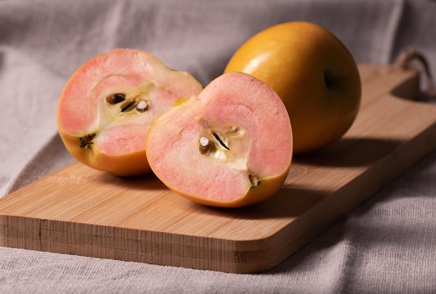 Fresh ripe red apples cut in half on bamboo chopping board