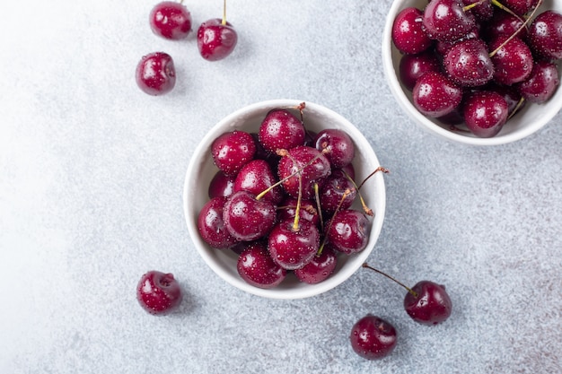 Fresh ripe red cherries in a white bowl on a gray stone 