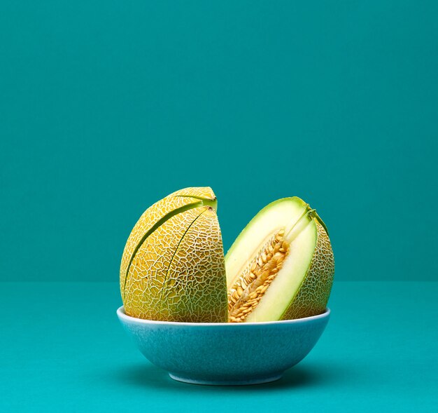 Fresh ripe sliced melon in a bowl on turquoise color background