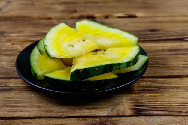 Fresh ripe sliced yellow watermelon in a plate on a wooden table