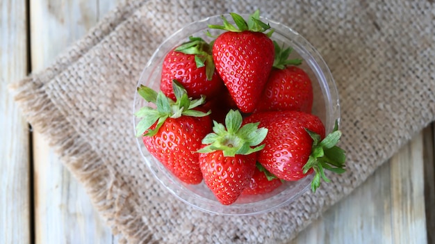 Fresh ripe strawberries in a plastic bowl