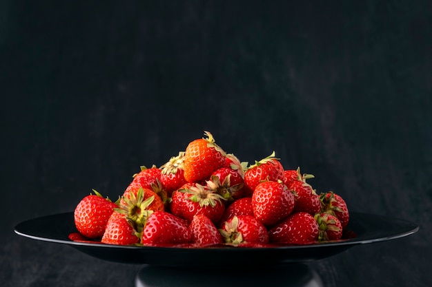 Fresh ripe strawberries , side view. Red berries, seasonal fruits. Sweet mouth-watering strawberry. Black background.