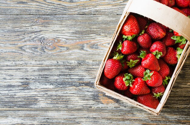 Fresh ripe strawberries in a wooden basket on a wooden background. Organic juicy berries.