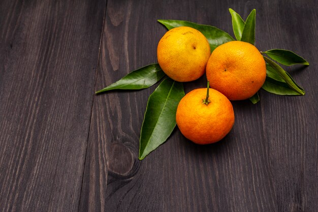 Fresh ripe tangerines with leaves on wooden table