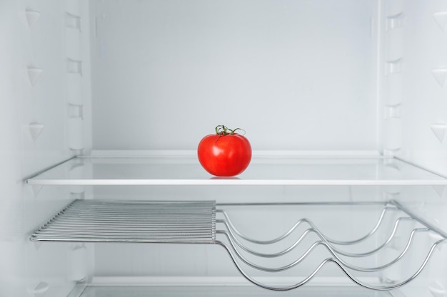 Photo fresh ripe tomato on empty shelf in refrigerator