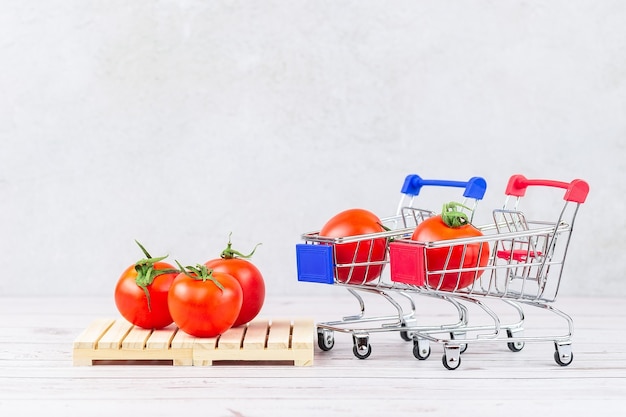 Fresh ripe tomatoes in a grocery cart and on a pallet, warehouse concept