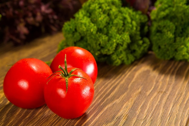 背景にグリーンサラダと木製のテーブルの上の新鮮な完熟トマト新鮮な野菜