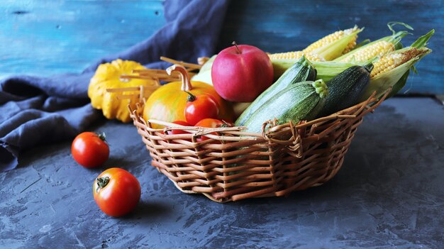 コンクリートのテーブルの上のバスケットの新鮮な熟した野菜の種類有機天然物