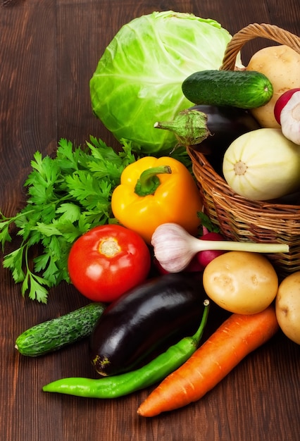 Foto verdure mature fresche in un canestro sulla tavola di legno