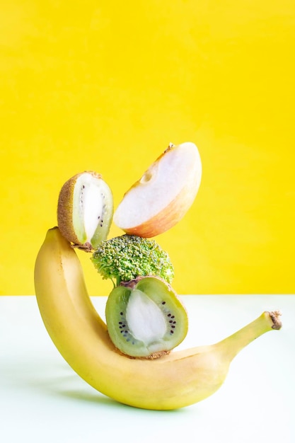 Fresh ripe vitamin vegan vegetables and fruits on table Equilibrium floating food balance on green yellow background creative concept