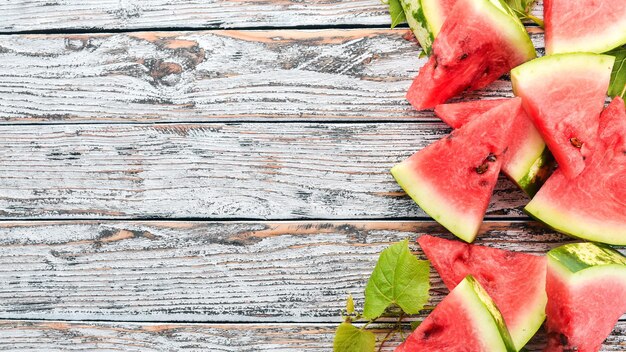 Foto anguria fresca e matura melone su fondo di legno bianco spazio libero per il testo vista dall'alto