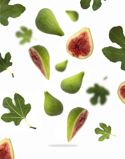 Fresh ripe whole and cut green figs with leaves on white isolated background flying in air fresh ripe