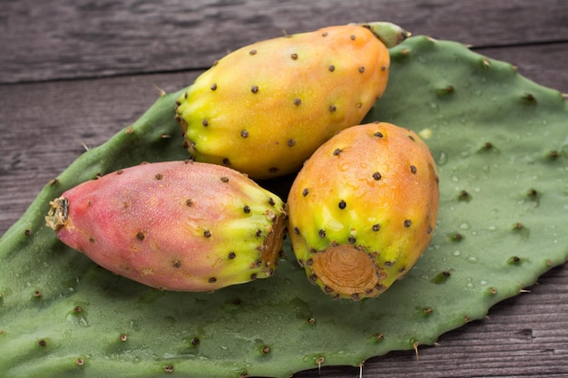 Fresh ripe whole prickly pears a leaf of the plant on wooden vintage background