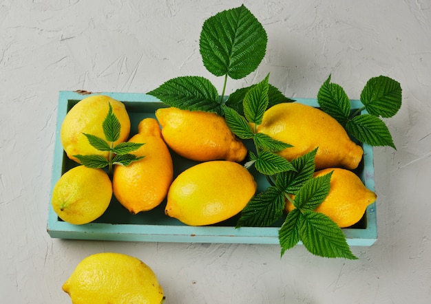 Fresh ripe whole yellow lemons on a blue wooden board