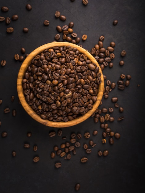 Foto chicchi di caffè arrostiti freschi in una ciotola di legno sulla pietra nera