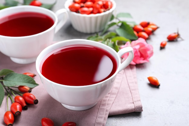 Fresh rose hip tea and berries on light table closeup